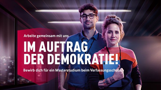 Die Aufnahme zeigt ein Kampagnenbild, auf dem zwei Personen zu sehen sind mit dem Schriftzug Im Auftrag der Demokratie