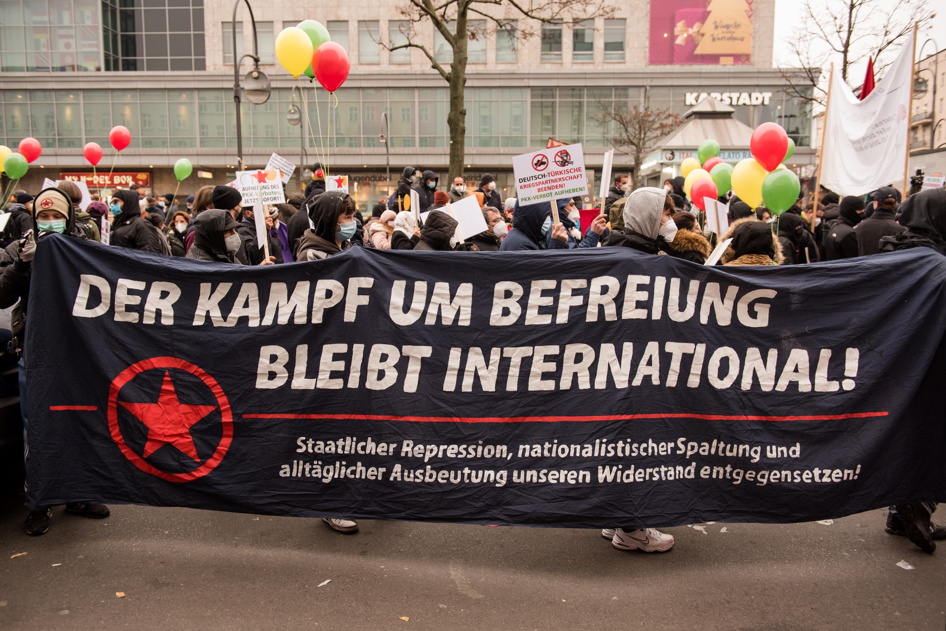 Die Aufnahme zeigt einen Protestmarsch am 27.11.2021 in Berlin mit dem Transparent "Der Kampf um Befreiung bleibt international"