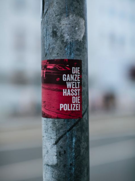 Die Aufnahme zeigt ein Plakat, das auf einen Mast geklebt ist, mit der Aufschrift "Die ganze Welt hasst die Polizei" 